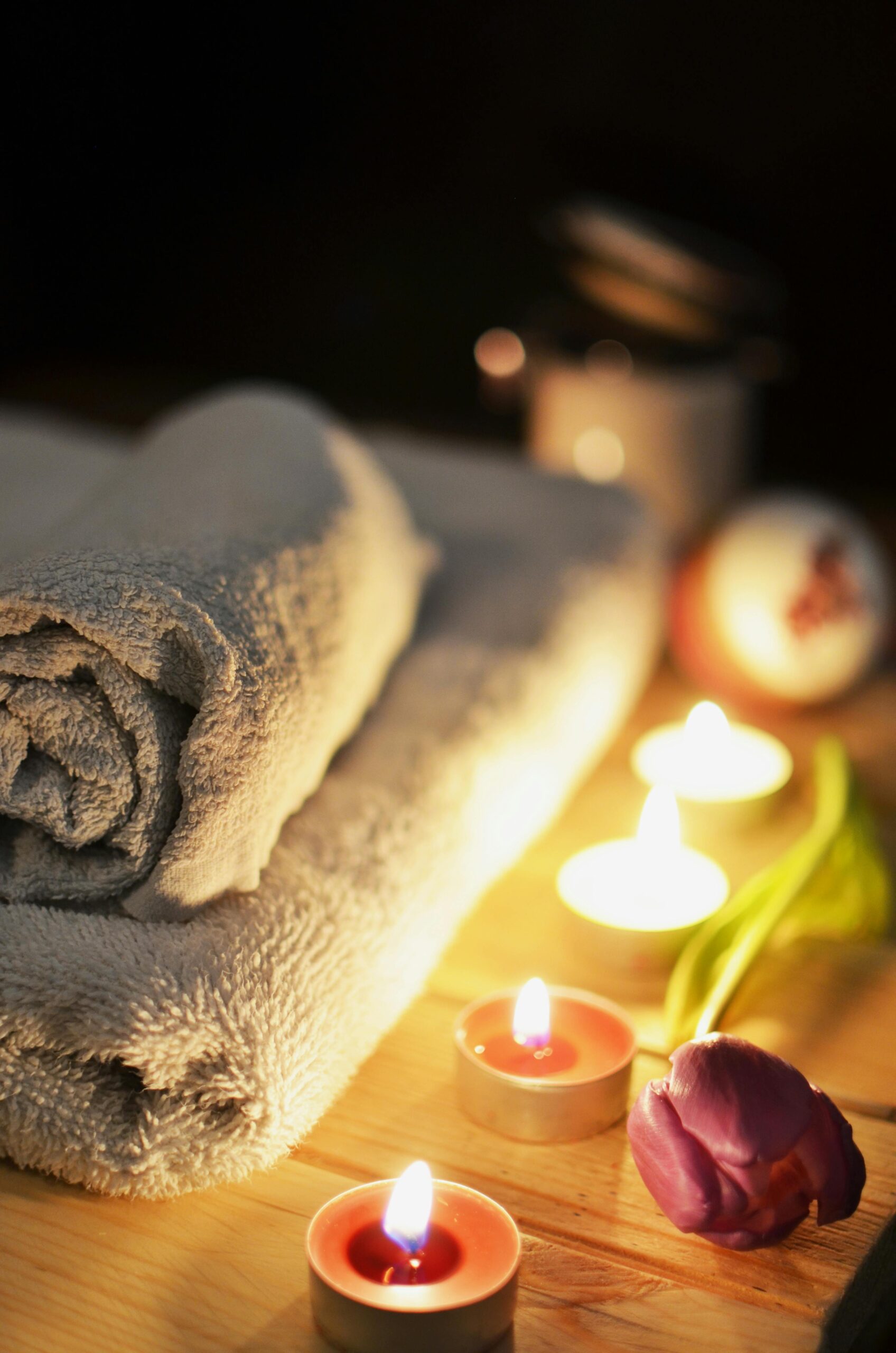 Relaxing spa atmosphere with candles, towels, and a tulip, perfect for wellness and self-care.